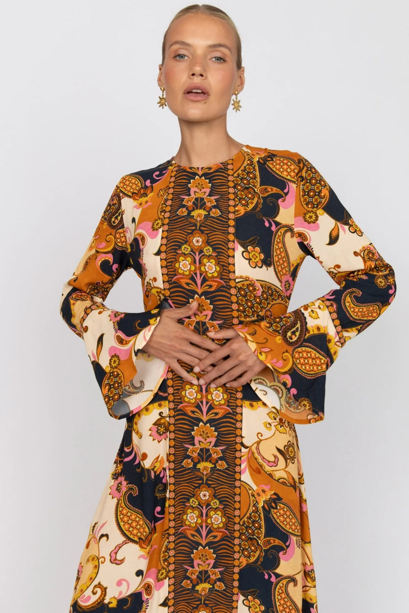 Woman wearing a long-sleeve dress with a colorful pattern on a white background