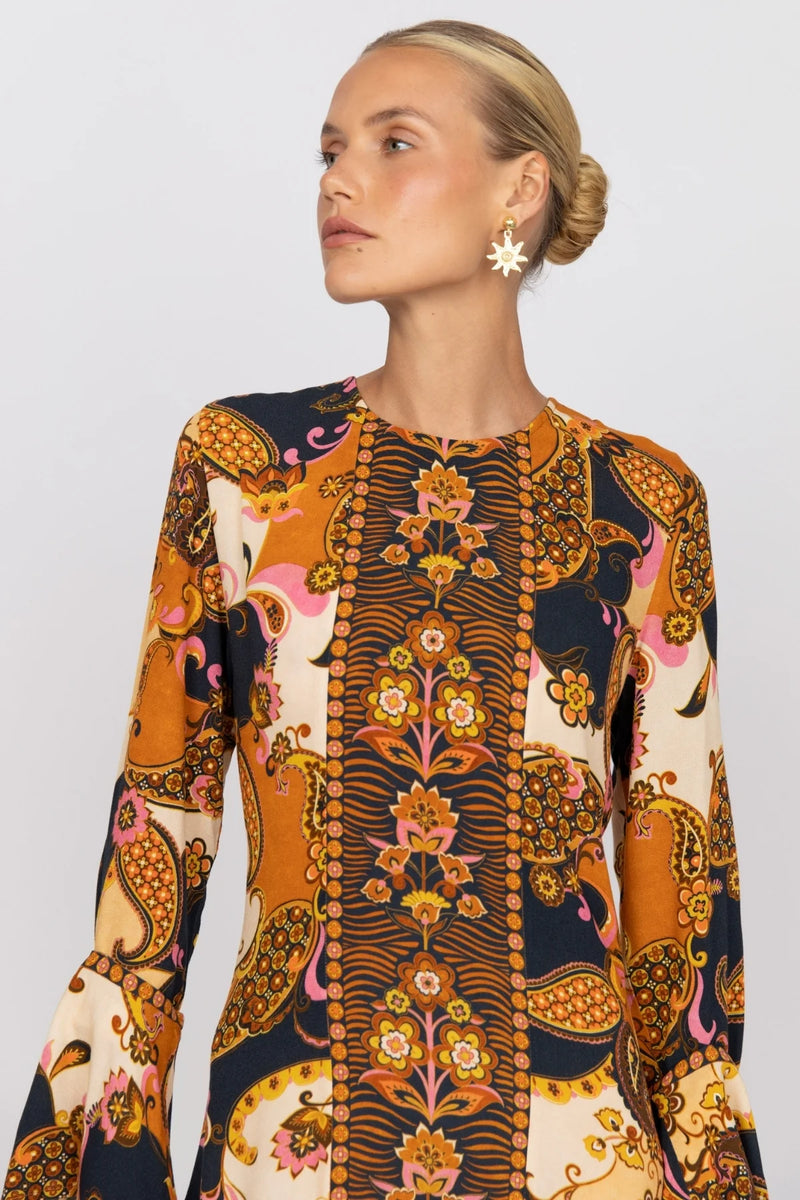 Woman wearing a long-sleeve dress with a colorful pattern on a plain background