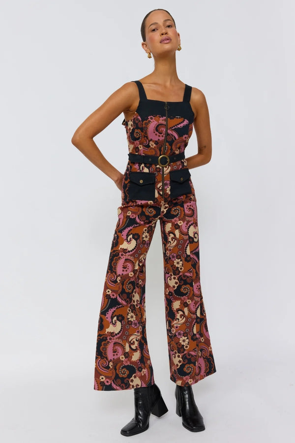 Model wearing a patterned jumpsuit with a belt on a white background