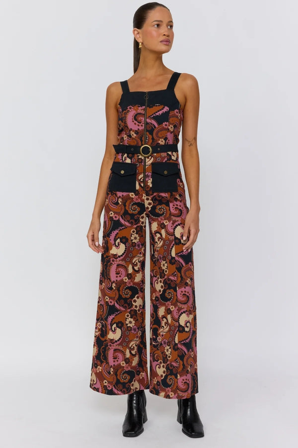 Woman wearing a patterned jumpsuit with a belt on a white background