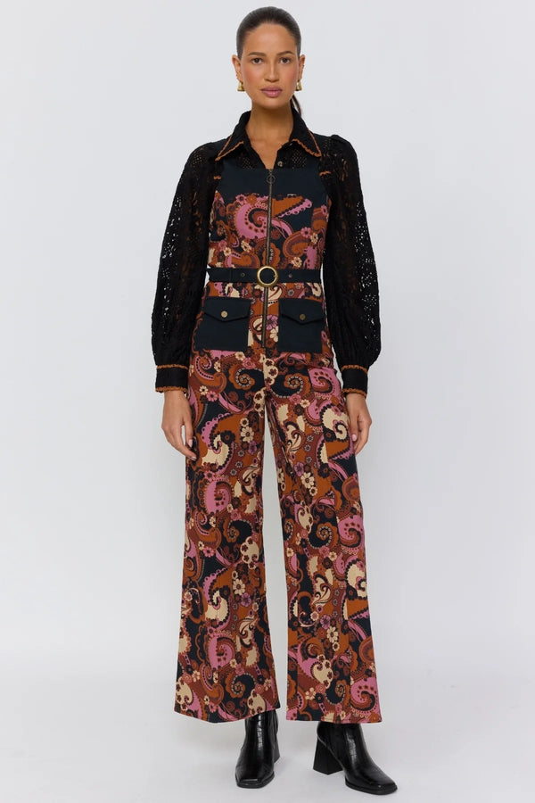 Woman wearing a patterned jumpsuit with a black shirt on a white background