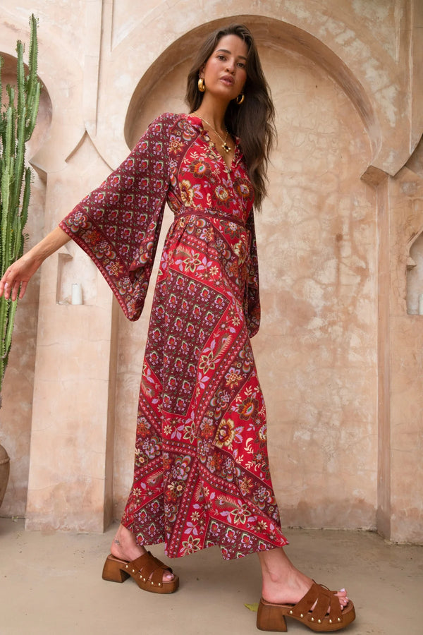 Woman wearing a red patterned dress standing in front of an archway.