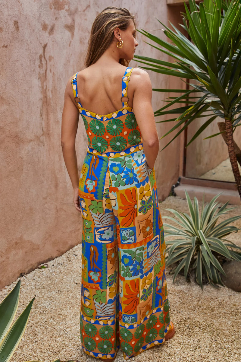 Woman wearing a colorful patterned jumpsuit standing in a garden setting.
