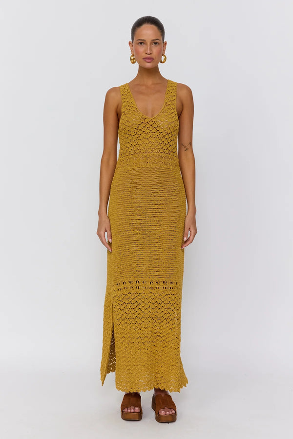 Woman wearing a mustard yellow crochet dress on a white background