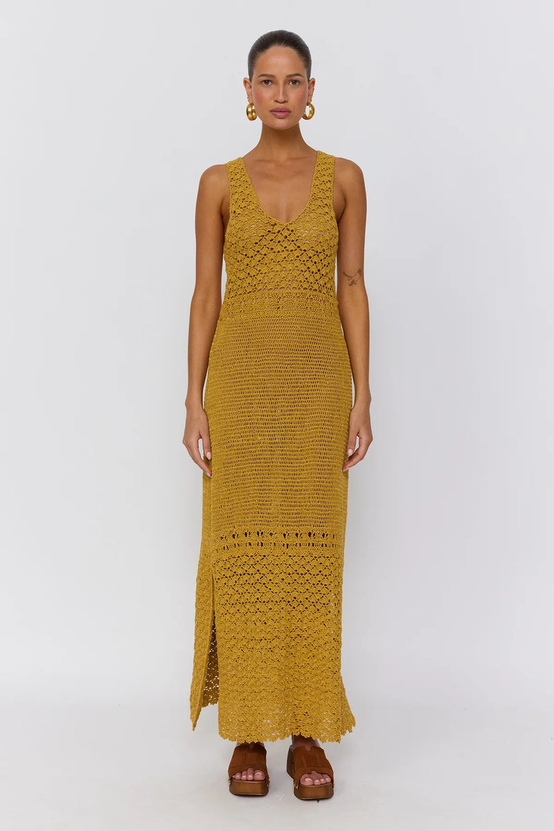 Woman wearing a mustard yellow crochet dress on a white background