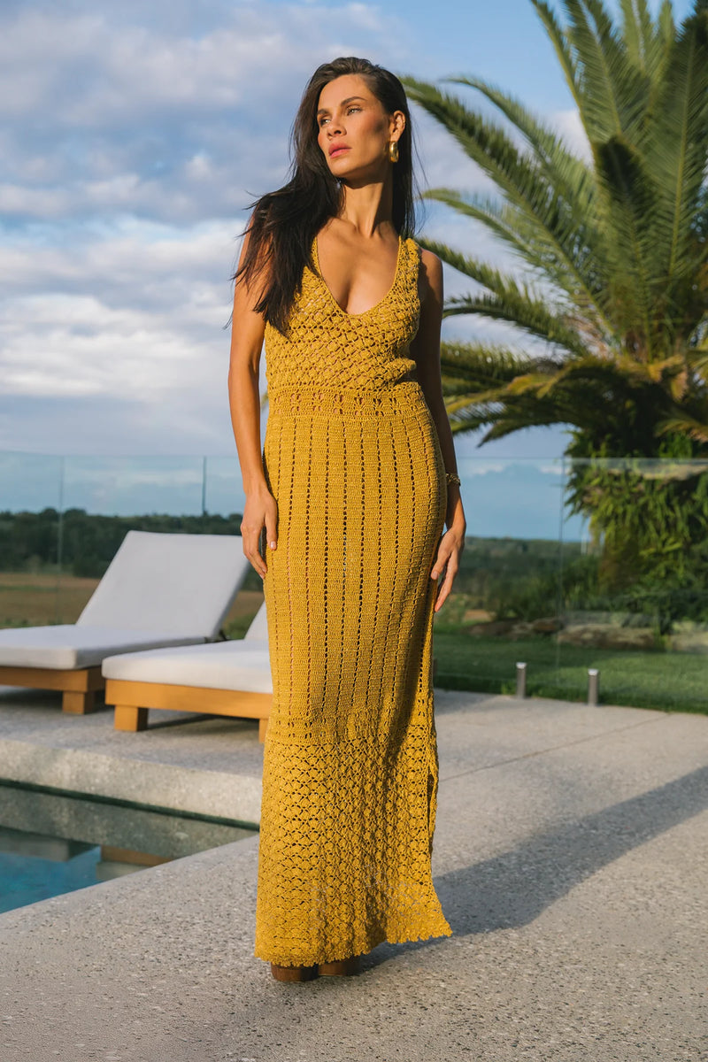 Woman in a yellow dress standing by a pool with palm trees in the background