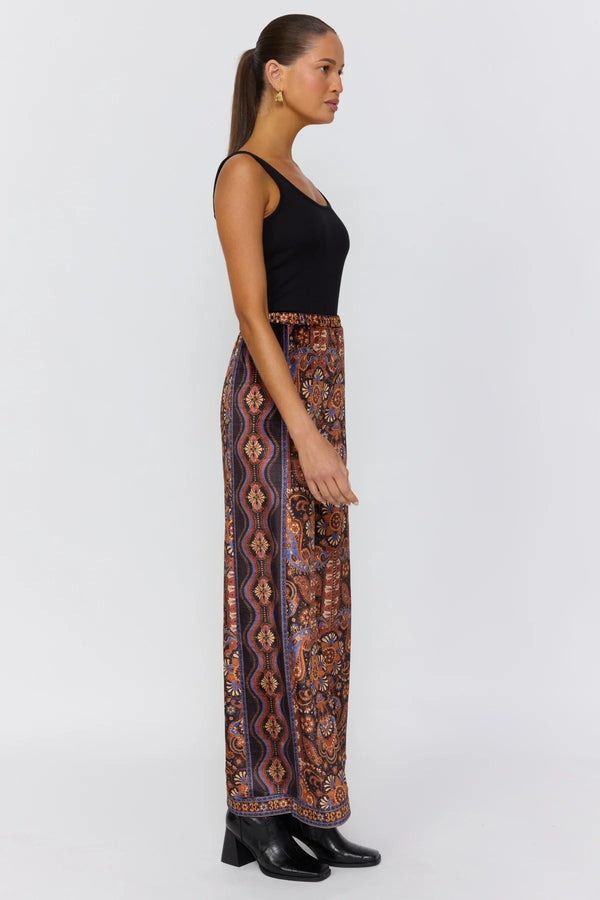 Woman wearing a black top and patterned pants on a white background