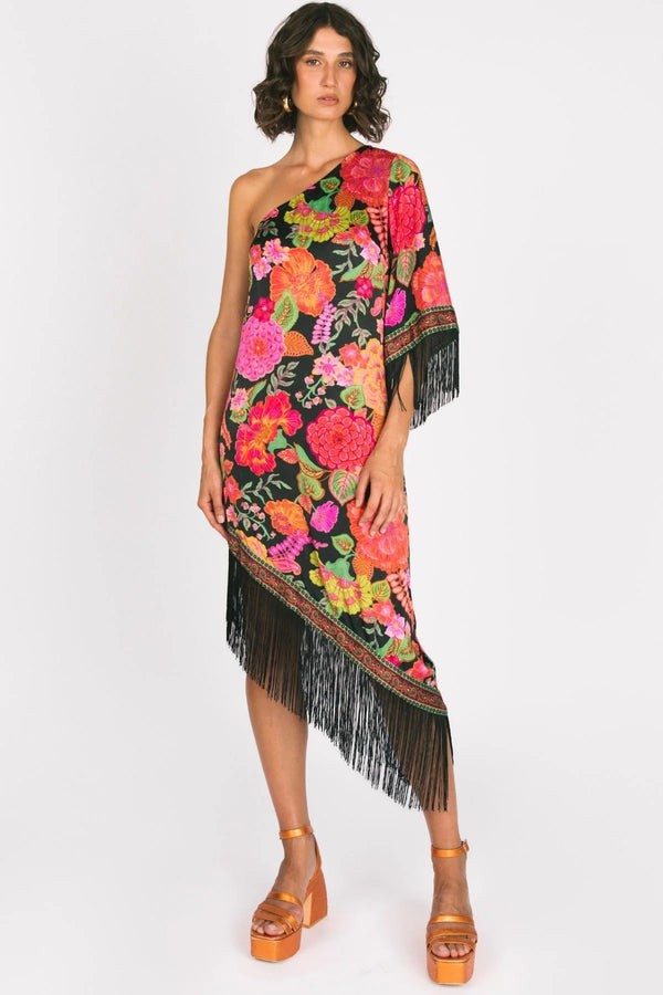 Woman wearing a colorful floral one-shoulder dress with fringe on a white background