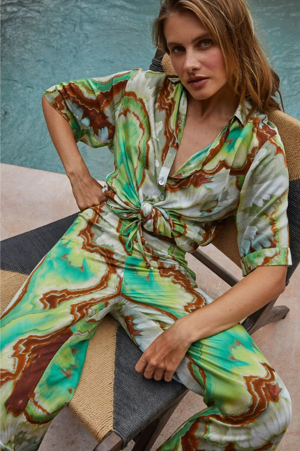 Woman wearing a colorful tie-dye outfit sitting on a chair.