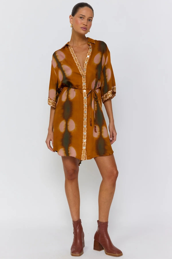 Woman wearing a patterned dress with gold accents on a white background