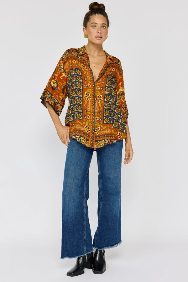 Woman wearing a patterned shirt and blue jeans on a white background