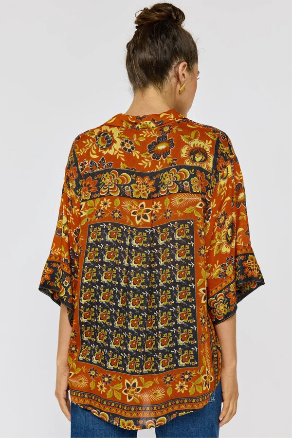 Woman wearing a patterned shirt with a plain background