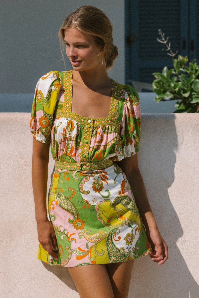 Woman wearing a colorful patterned dress standing outdoors.
