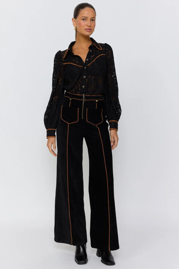 Woman wearing a black outfit with gold accents on a white background