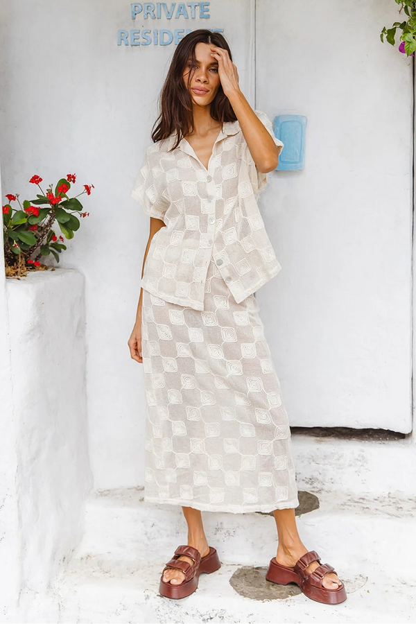Woman in a white checkered dress standing in front of a white door with 'Private Residence' sign.