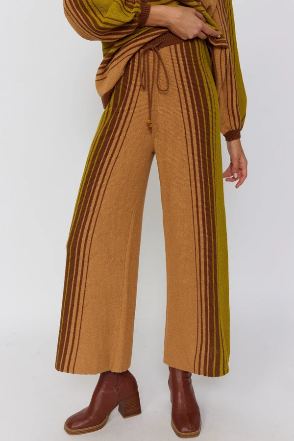 Person wearing a brown and yellow striped outfit with brown boots on a white background