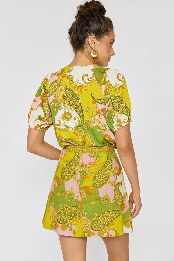 Woman wearing a colorful patterned outfit on a plain background