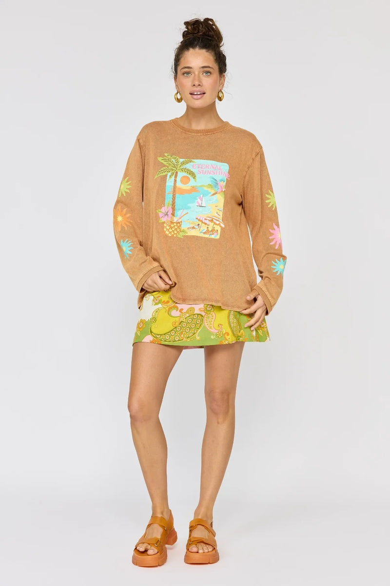 Woman wearing a brown oversized shirt with a graphic design and a colorful skirt on a white background