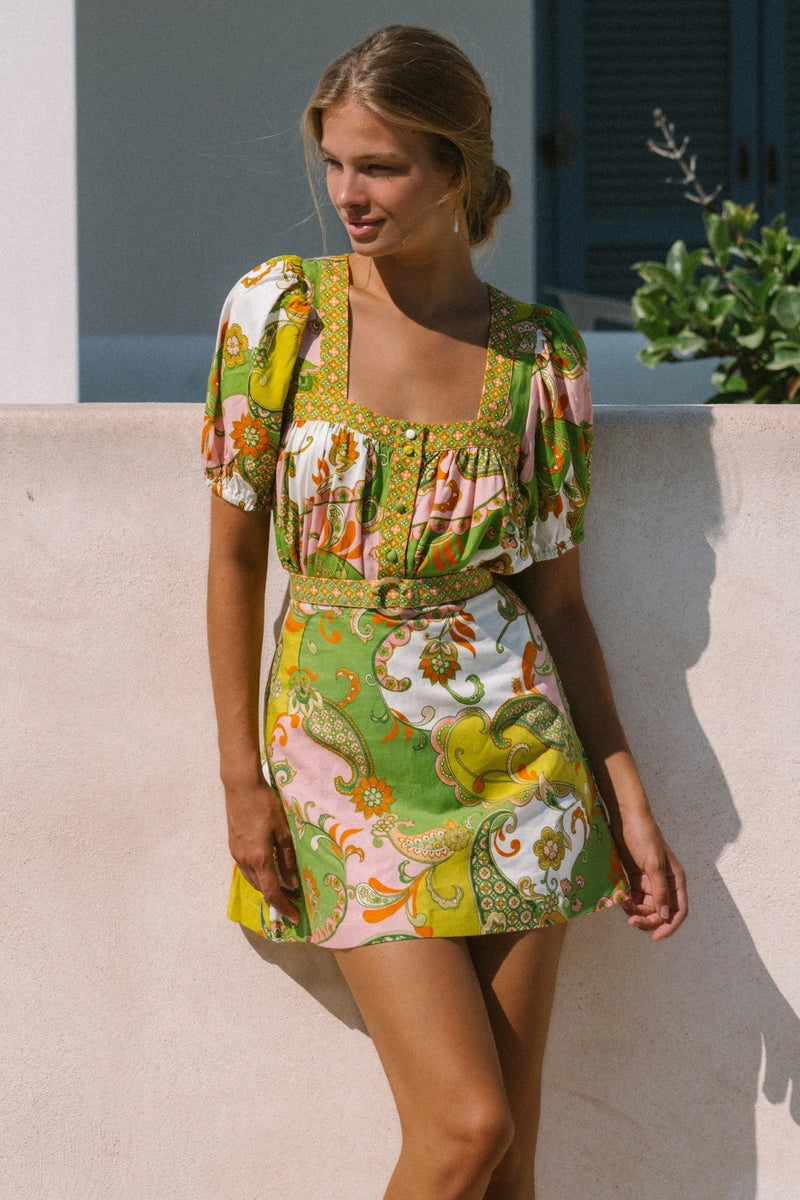 Woman wearing a colorful floral dress standing outdoors.
