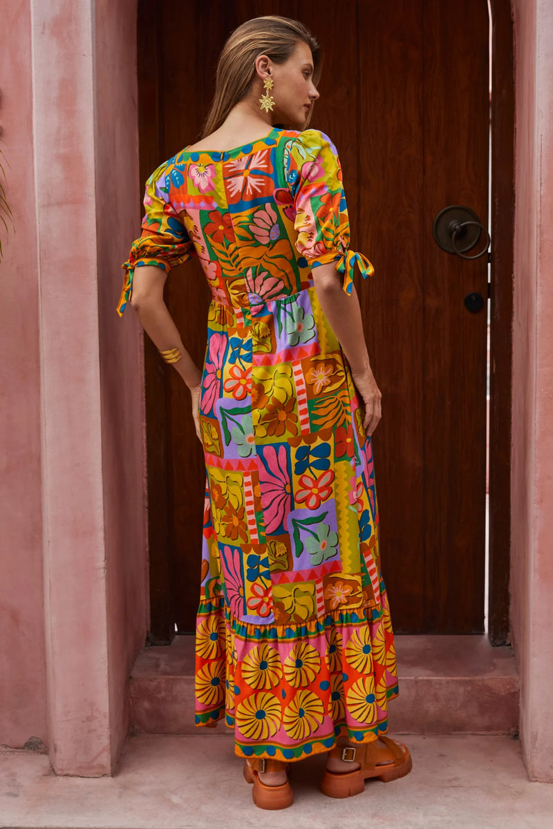 Woman wearing a colorful patterned dress standing in a doorway.
