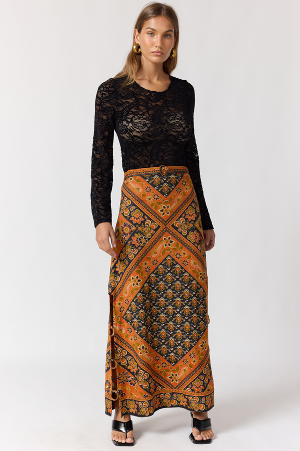Woman wearing a black lace top and patterned orange skirt on a white background