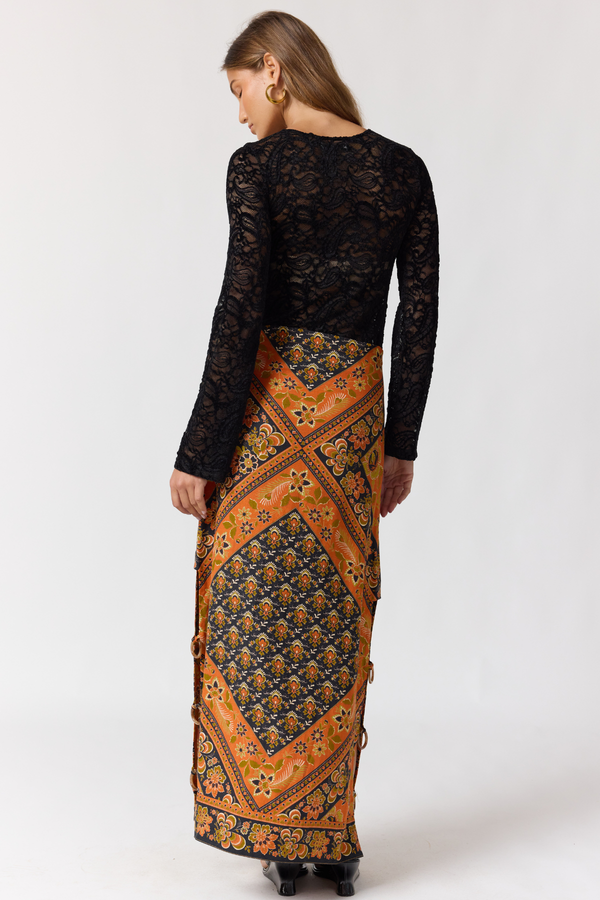 Woman wearing a black lace top and patterned skirt on a white background