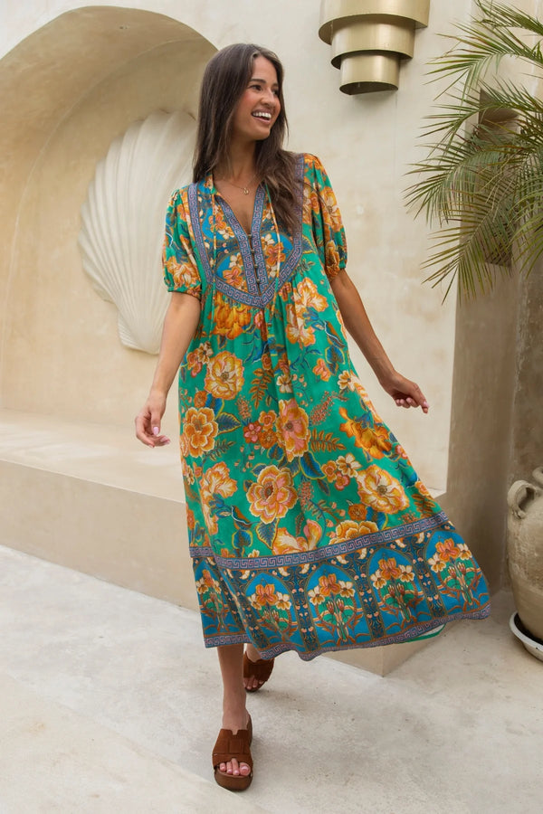 Woman in a floral dress standing outdoors with decorative elements in the background