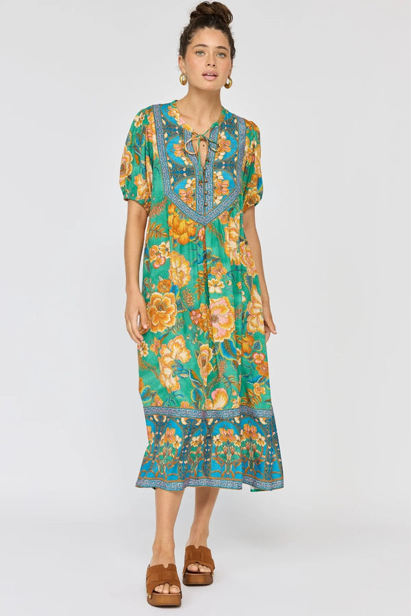 Woman wearing a floral dress with a green and blue pattern on a white background