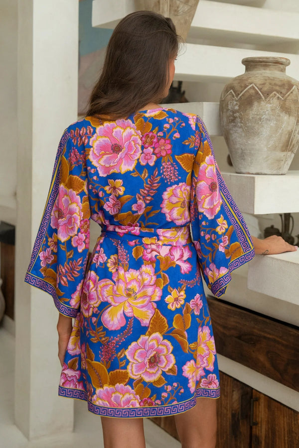 Woman wearing a colorful floral dress in a home setting.