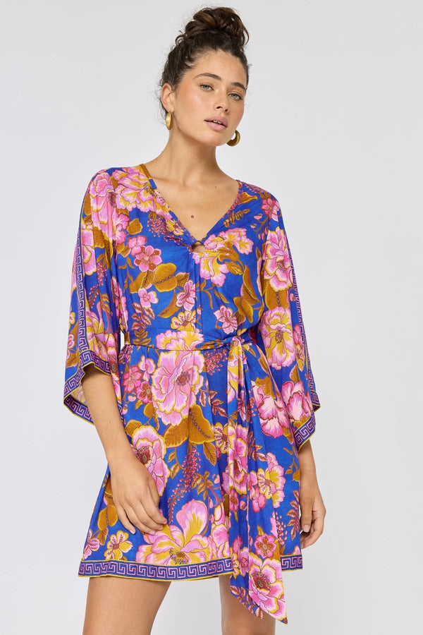 Woman wearing a colorful floral dress on a plain background