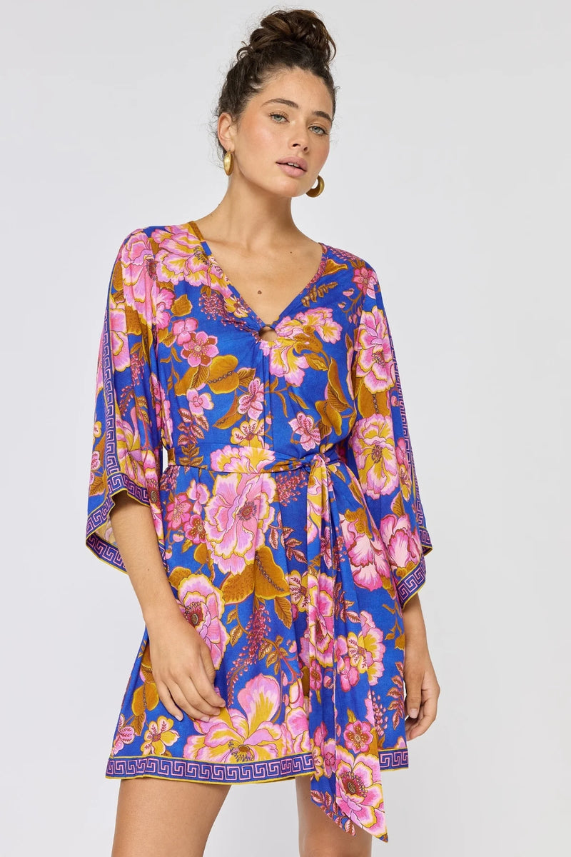 Woman wearing a colorful floral dress on a plain background