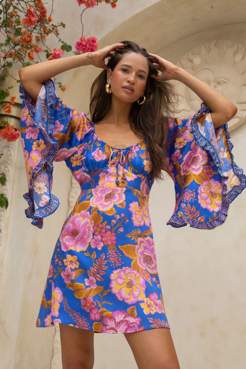 Woman wearing a colorful floral dress with a decorative background