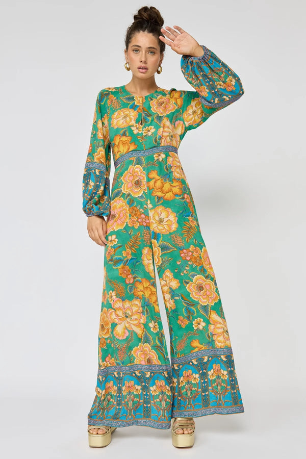 Woman wearing a floral dress with a green and orange pattern on a white background