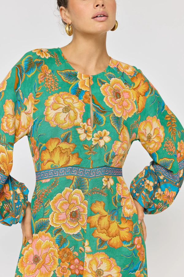 Woman wearing a floral dress with a green and orange pattern on a white background