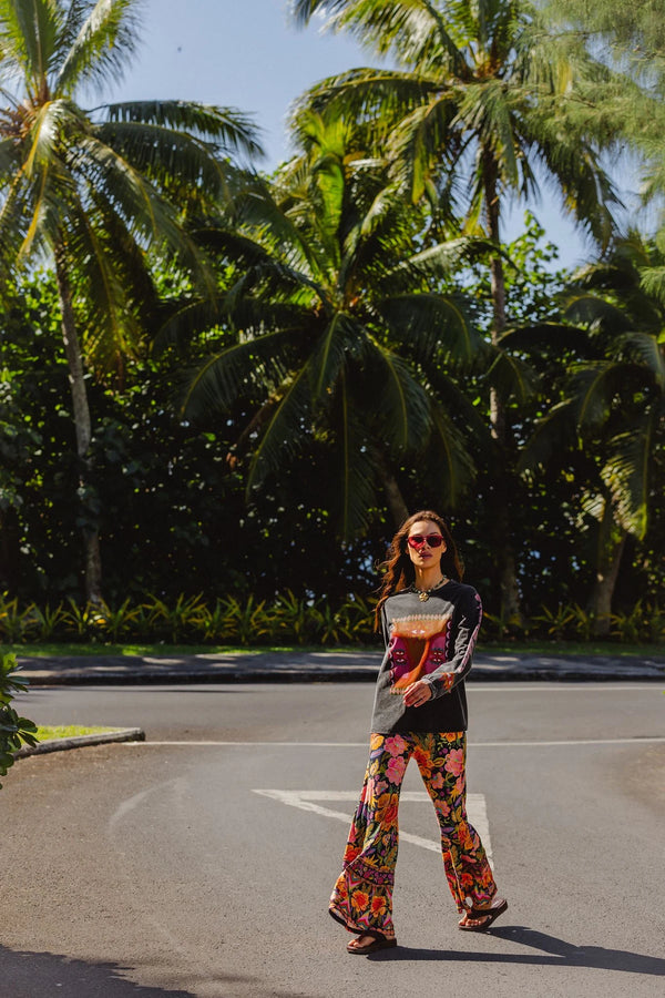 Woman in colorful outfit standing on a road with palm trees in the background