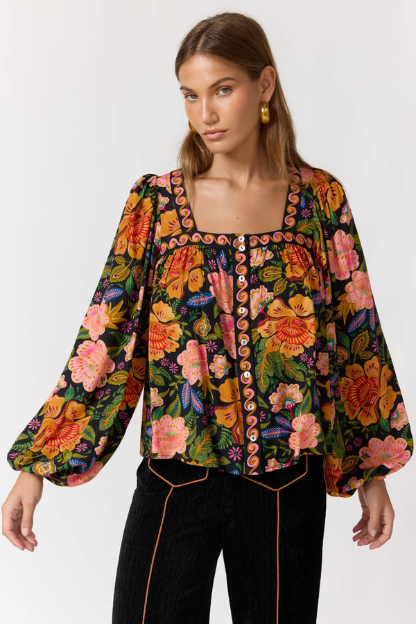 Woman wearing a colorful floral blouse against a white background