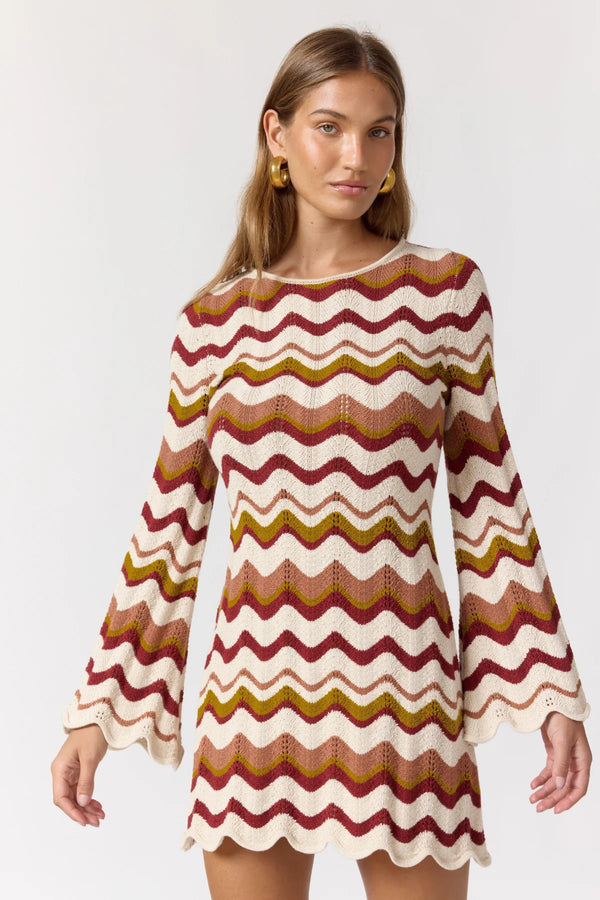 Woman wearing a patterned dress with long sleeves on a white background