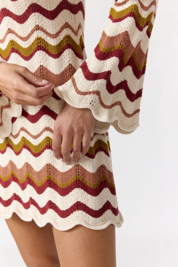 Close-up of a person wearing a colorful knitted dress with a white background