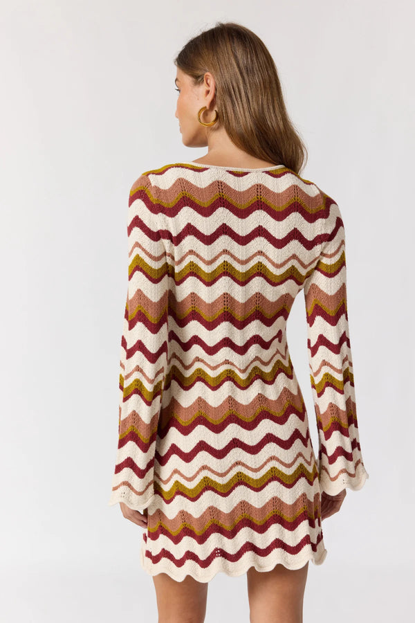 Woman wearing a patterned dress with long sleeves on a white background