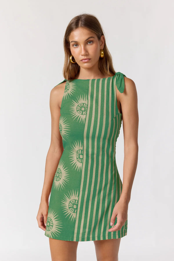 Woman wearing a green dress with sun pattern on a white background