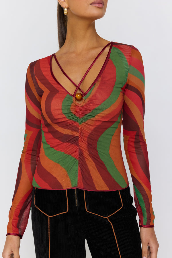 Woman wearing a colorful patterned top with long sleeves on a white background