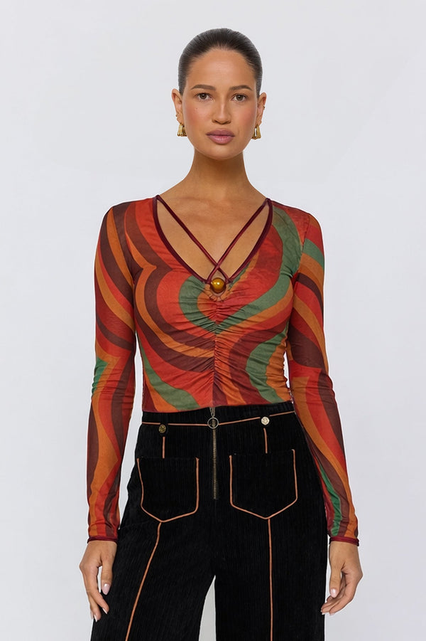 Woman wearing a patterned top and black pants on a white background