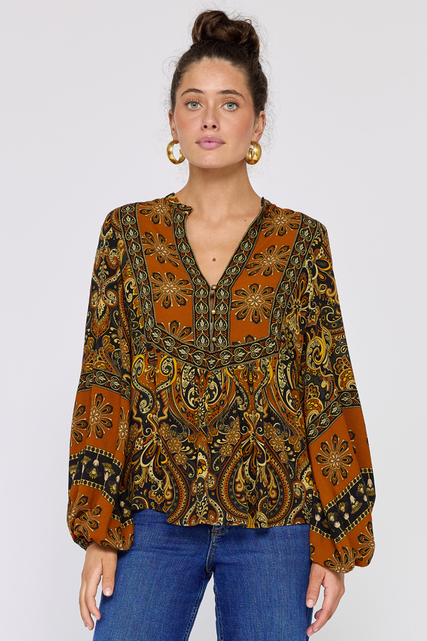 Woman wearing a patterned blouse with long sleeves on a white background