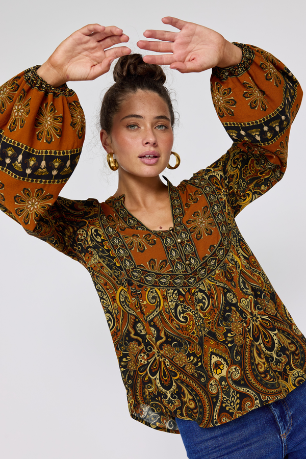 Woman wearing a patterned blouse with long sleeves on a white background