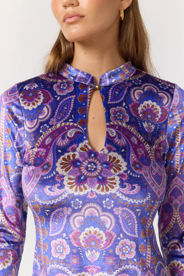 Close-up of a person wearing a long-sleeve top with a colorful paisley pattern.