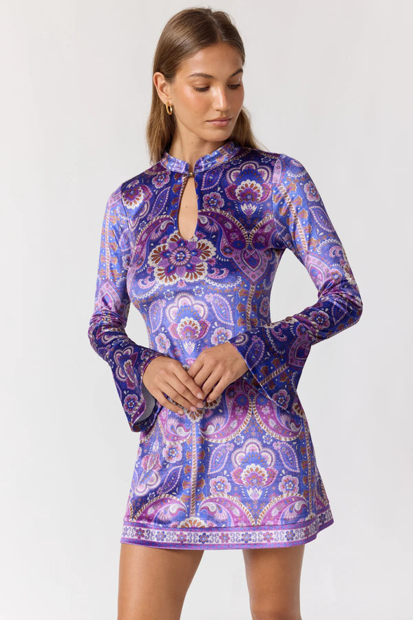Woman wearing a purple paisley patterned dress on a white background