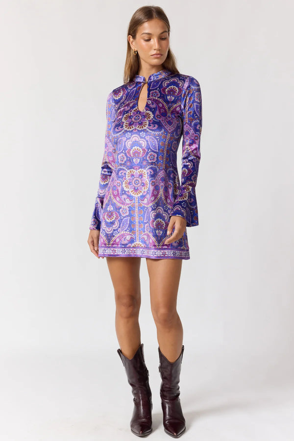 Woman wearing a purple patterned dress with long sleeves on a white background