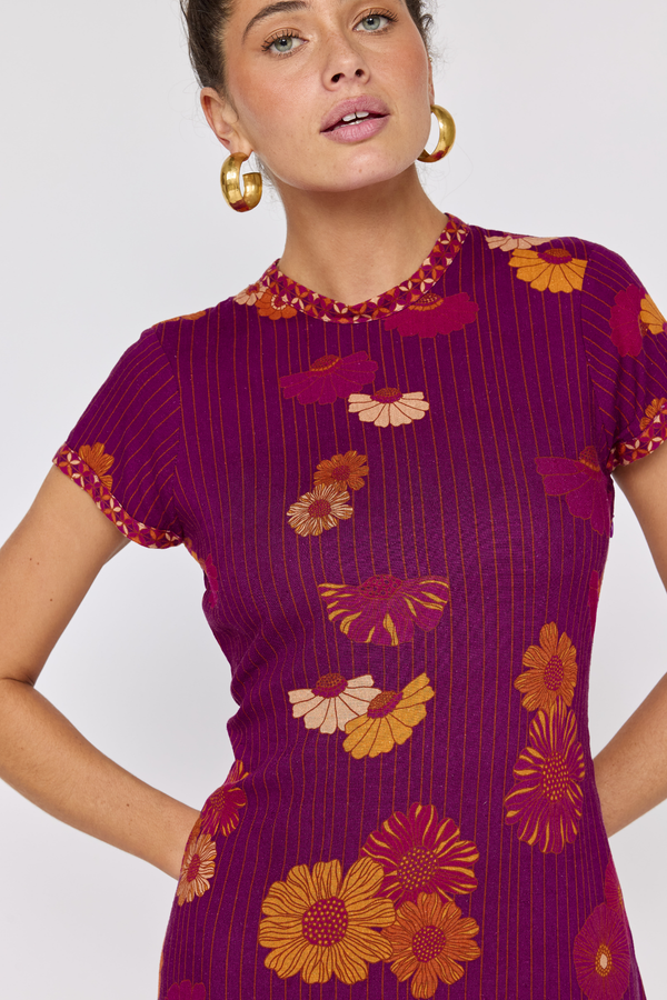 Woman wearing a purple dress with floral patterns on a white background