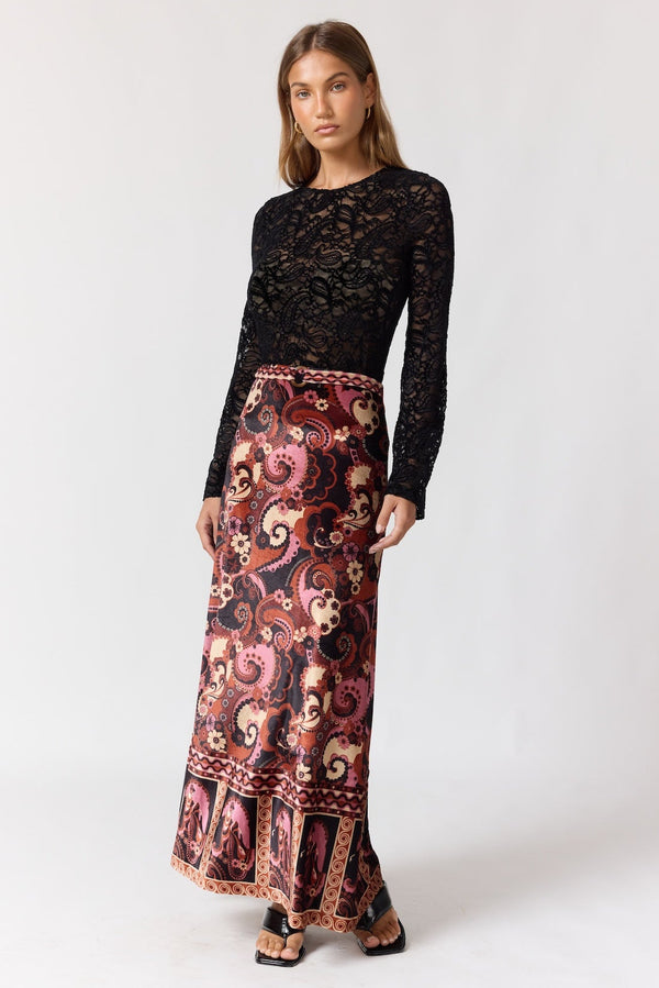 Woman wearing a black lace top and patterned skirt on a white background