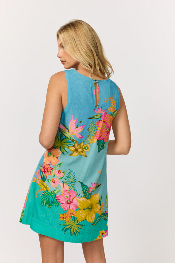A woman shown from the back wearing a sleeveless sky blue to aqua tropical floral shift mini dress with a keyhole back, against a light gray studio background.